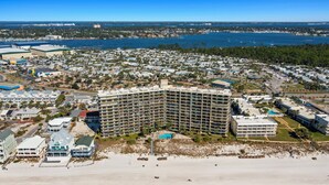 Un hotel grande con varios pisos y una piscina, situado cerca de la playa y del agua.