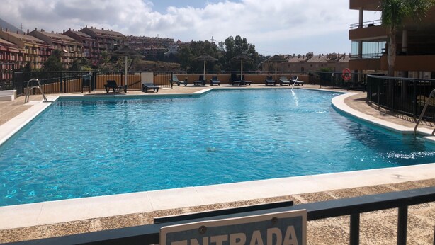 Una piscina con sillas de descanso y un letrero que dice "ENTRADA".