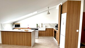 Una cocina moderna con una isla central, armarios de madera, microondas, cafetera y lavavajillas.