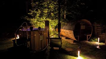 Ein Whirlpool und ein Holzbottich in einem Garten bei Nacht.