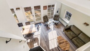 Amplia sala de estar con mesa de comedor de madera, dos sofás y un gran ventanal con vistas al exterior.