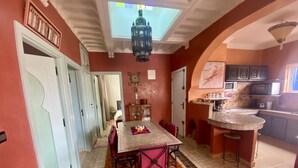 A dining area with a table and chairs, a kitchen with a microwave and sink, and a ceiling with a skylight. - Apartment with distant ocean view, sleeps 4/6 (Essaouira)