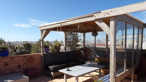 A rooftop terrace with a wooden pergola, seating area, and potted plants. - Apartment with distant ocean view, sleeps 4/6 (Essaouira)
