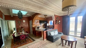 A spacious living area with a sofa, dining table, and kitchen in the background. - Apartment with distant ocean view, sleeps 4/6 (Essaouira)