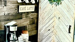 A rustic interior with a wooden wall, a coffee station, and a door with a decorative wreath. - Peaceful Charming Tiny Home (Kyle)