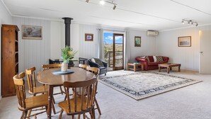 Ein geräumiges Wohnzimmer mit einem Holzessttisch, Stühlen, einem roten Sofa und einem großen Teppich.