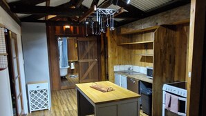 Eine rustikale Küche mit Holzbalken, einer zentralen Kochinsel und einem eingebauten Backofen.