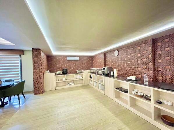Une cuisine moderne avec un mur de crédence décoré d’un motif en briques, un coin repas avec une table et des chaises, et un meuble intégré contenant des ustensiles de cuisine.