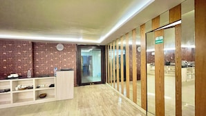 Un espace d’accueil moderne avec un mur en briques, un comptoir d’accueil et une cloison en verre donnant accès à des toilettes.
