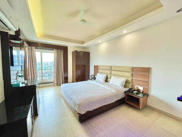Une chambre d’hôtel avec un grand lit, une armoire, un bureau avec une chaise, une télévision et une fenêtre avec des rideaux.