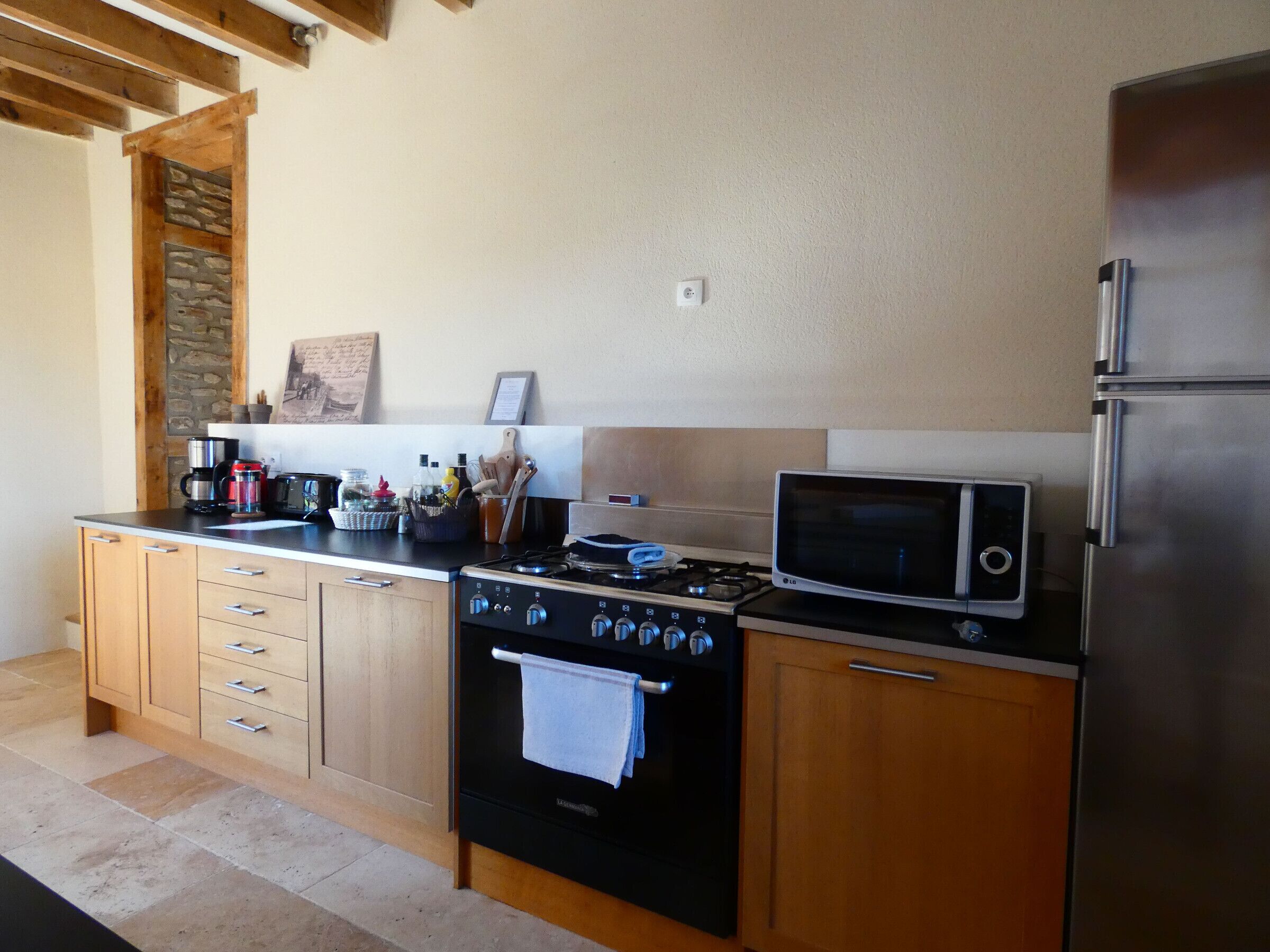 A kitchen with wooden cabinets, a stove, a microwave, and a refrigerator.