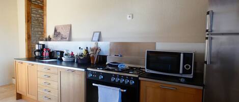 A kitchen with wooden cabinets, a stove, a microwave, and a refrigerator.