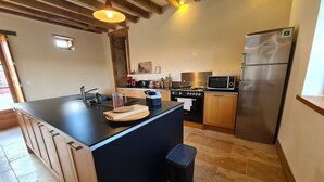 Een moderne keuken met een centraal eiland, roestvrijstalen apparatuur en houten kastjes.