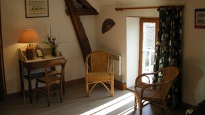 A cozy room with a wooden desk, two wicker chairs, a lamp, and a framed picture on the wall. - Comfortable rooms on a farm in the heart of Berry (Montchevrier)