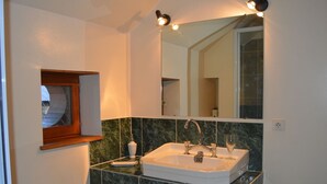 A bathroom with a white sink, green marble tiles, a mirror, and a wooden medicine cabinet. - Comfortable rooms on a farm in the heart of Berry (Montchevrier)