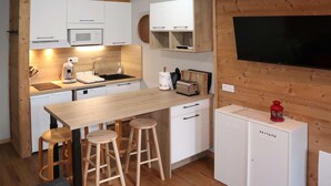 A compact kitchen with white cabinets, a wooden countertop, and stools. - Renovated studio for 5, near lifts, balcony (Les Orres)
