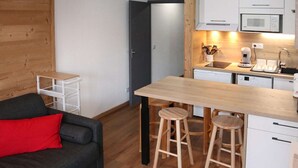 A compact kitchen with a wooden countertop, two stools, a microwave, and a dishwasher. - Renovated studio for 5, near lifts, balcony (Les Orres)