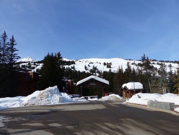 Ein schneegebdeckter Berg mit einem Skigebiet im Hintergrund.