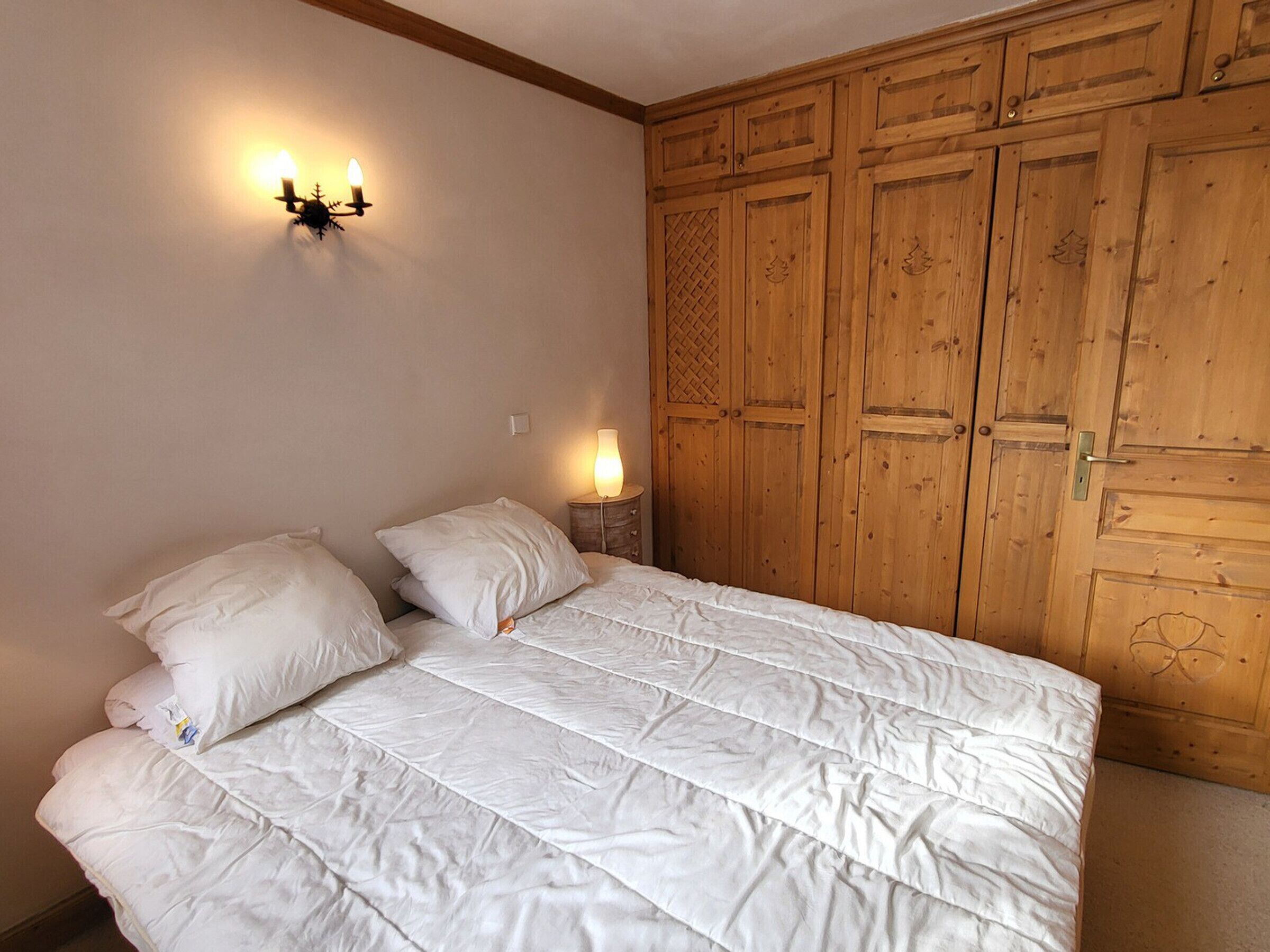 Un dormitorio con cama, dos lámparas de noche y un armario de madera.