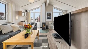 A modern living room with a large TV, wooden furniture, and a cozy fireplace.