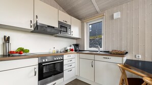 Una cocina moderna con electrodomésticos de acero inoxidable, encimera de madera y ventana con vistas al exterior.
