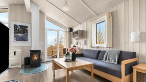 Una sala de estar acogedora con chimenea, un sofá, una mesa de centro y un comedor.