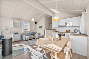 Een moderne keuken met witte kasten, een eettafel en een inbouwoven.