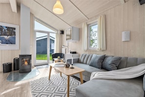 Een knusse woonkamer met een bank, een tafel, een open haard en een groot raam.