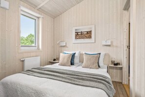 A bedroom with a large bed, a window, a framed picture on the wall, and bedside lamps. - Waldpalast - Comfortable Vacation Home for 4 to 6 People with a Sauna   (St. Andreasberg)