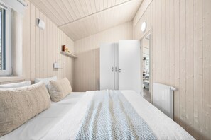 Une chambre à coucher avec un lit, une armoire, une étagère remplie de livres et un radiateur.