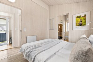 Een slaapkamer met een bed, een radiator, een deur naar een badkamer en een lijst met een afbeelding aan de muur.