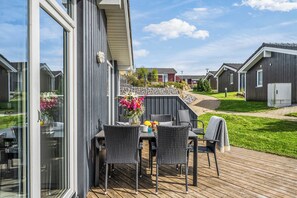 Une terrasse dotée de mobilier d’extérieur et agrémentée d’un arrangement floral.