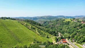 Ländliche Landschaft mit kurvenreichem Weg, grünen Feldern und verstreuten Häusern mit roten Dächern.
