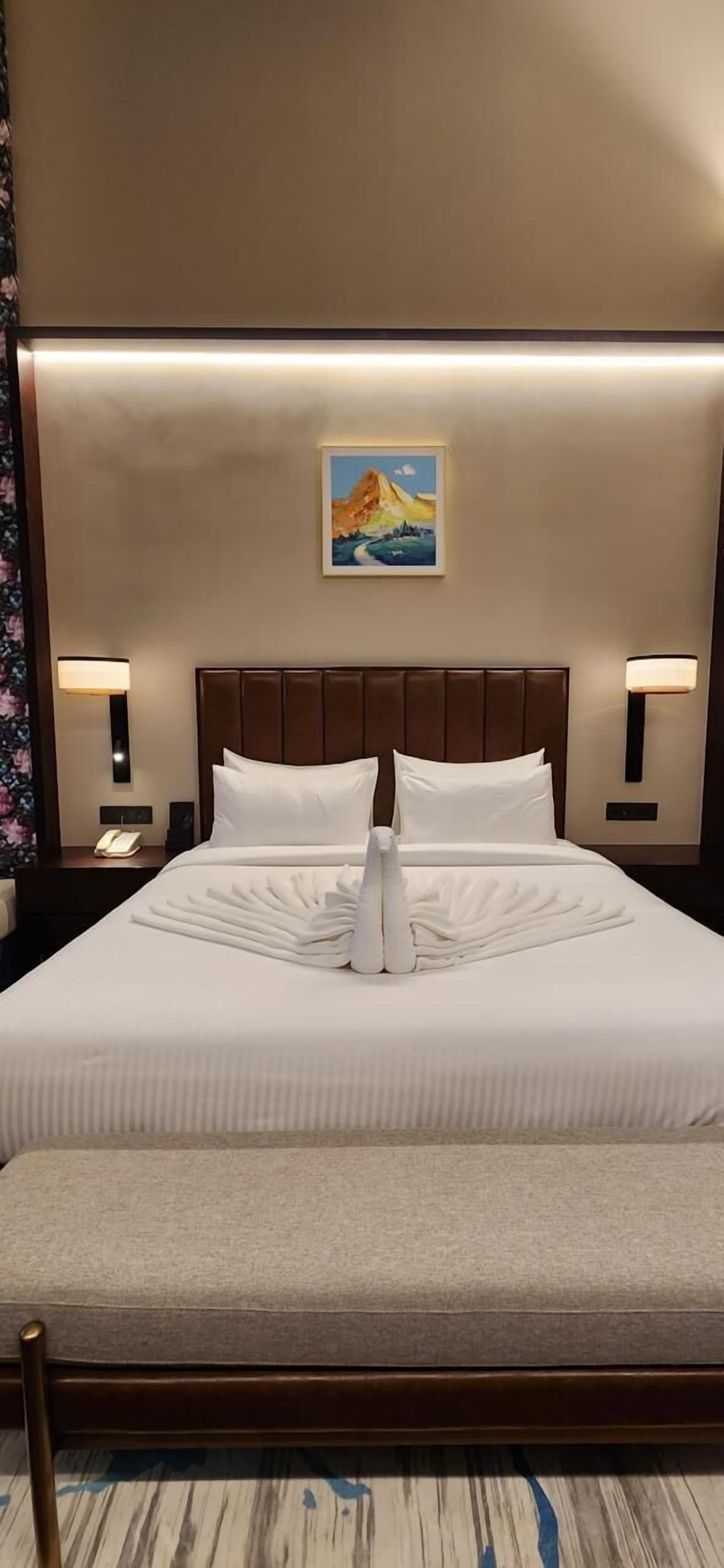 A neatly made bed with white linens, a headboard, and a bedside lamp on each side.