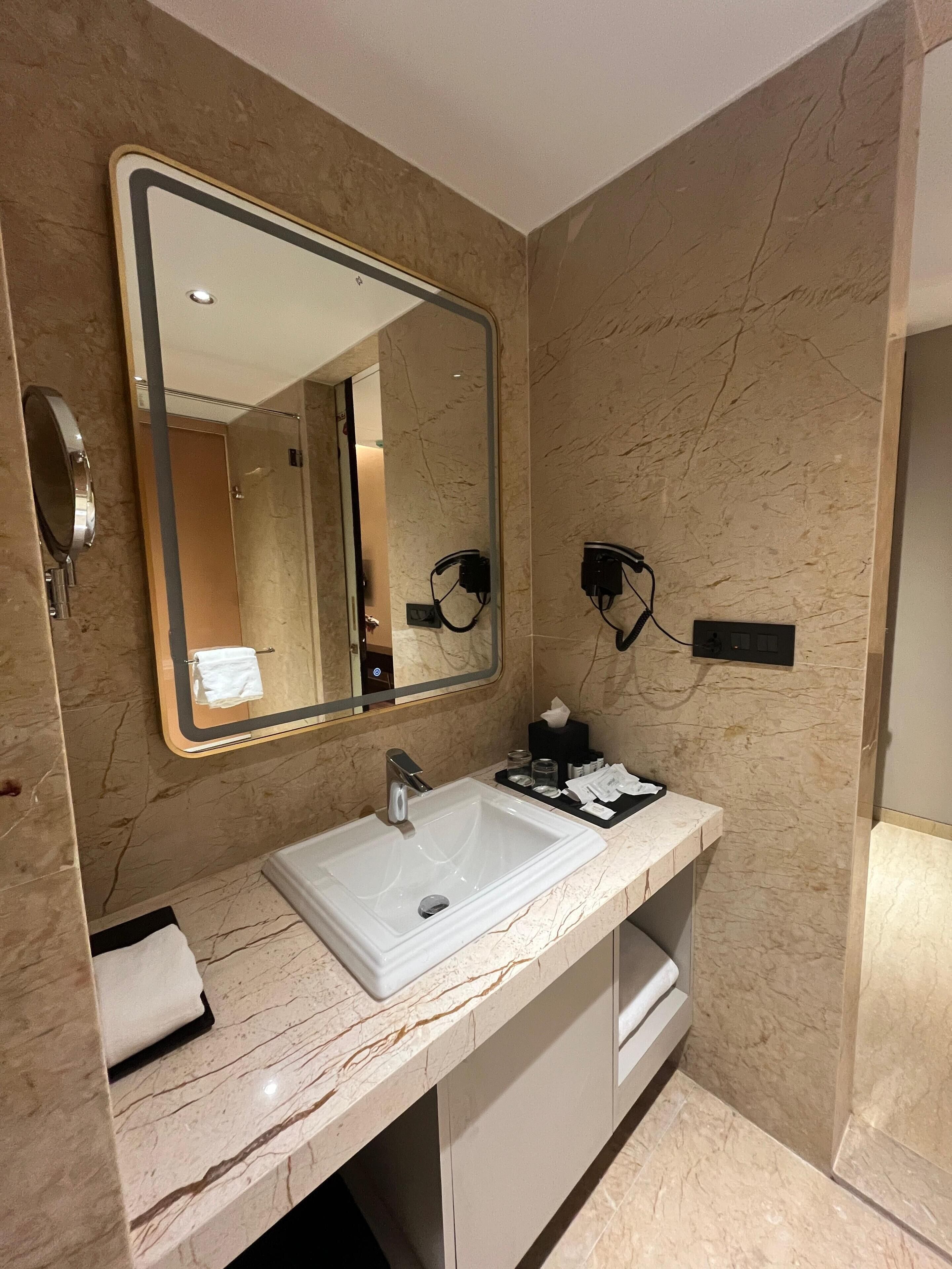A bathroom with a marble sink, a large mirror, and a towel rack.