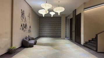 A modern hallway with a patterned floor, a seating area with cushions, and a staircase.