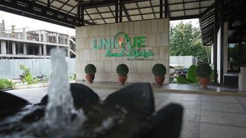 A building entrance with a sign reading "UNIQUE Resort & Lifestyle" and a water feature in the foreground.