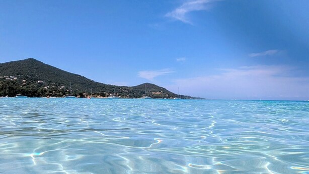 Une eau d’un bleu limpide, parsemée de légères ondulations, et une montagne qui se profile à l’horizon.