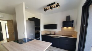 Une cuisine moderne avec un plan de travail en bois, des armoires noires, un four encastré et un micro-ondes.