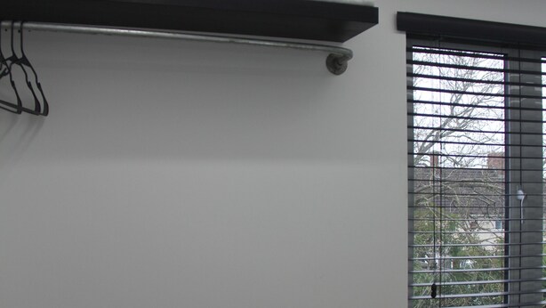 A room with a desk, a lamp, a kettle, and a window with blinds. - 122 Marshfield (Bristol)