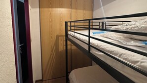 A bunk bed with a wooden wardrobe and a door in the background.