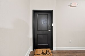 A black door with a number 1 sign, a doormat with 'hello' written on it, and an EXIT sign above the door.