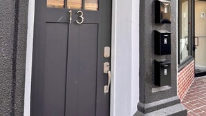 Una puerta negra con el número 13, un buzón y una ventana pequeña.