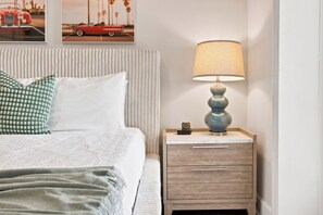 A neatly made bed with pillows, a bedside lamp, and a nightstand with a drawer.