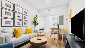 Una sala de estar moderna con sofá, mesa de centro, televisor y cuadros en la pared.