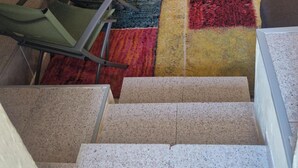 Una escalera alfombrada con una silla de metal y una mesa cerca.