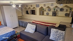 A cozy living area with a grey sofa, a striped blanket, and a white wardrobe.