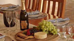 A dining table set with a bottle of Chandon wine, glasses, plates, and a variety of fruits and cheese.