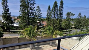 A pool area with a wooden deck, surrounded by trees and a view of a residential neighborhood.