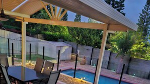 A covered patio with a pool, outdoor furniture, and a view of the backyard.